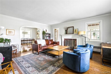 Living room featuring ornamental molding, radiator heating unit, a brick fireplace, and hardwood / wood-style flooring