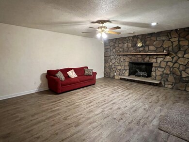Spacious living room with laminate flooring, ceiling fan & gas fireplace. 