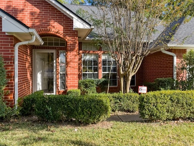 Property entrance featuring brick siding and a shingled roof