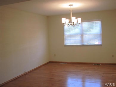 Unfurnished room with hardwood / wood-style floors and a chandelier