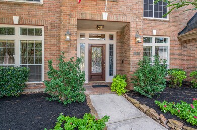 A winding sidewalk leads up to the covered front porch area adorned with coach lights and blooming foliage!