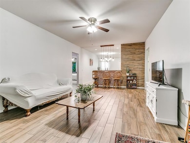 Living room featuring wood walls, light hardwood / wood-style flooring, and ceiling fan