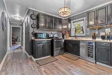 Kitchen with stainless steel appliances, wine cooler, light wood-style floors, a chandelier, and decorative light fixtures