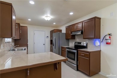 Kitchen with stainless steel appliances, a sink, under cabinet range hood, decorative backsplash, and recessed lighting