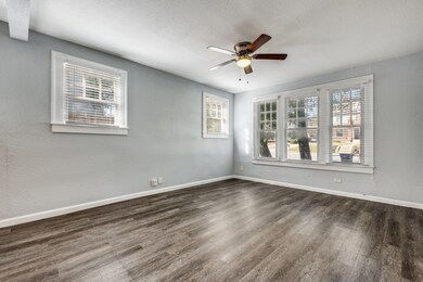 Empty room with a textured wall, a textured ceiling, dark wood-type flooring, and a ceiling fan