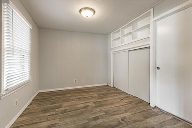 Unfurnished bedroom with wood finished floors, multiple windows, and a closet