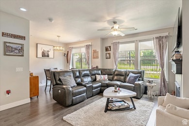 Living room with wood finished floors, ceiling fan, a textured ceiling, and a fireplace