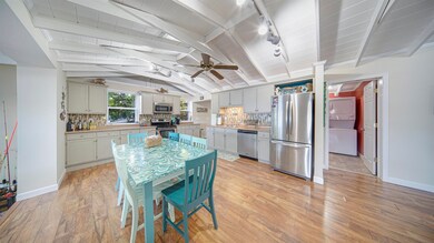 Kitchen featuring ceiling fan, stainless steel appliances, lofted ceiling with beams, and light hardwood / wood-style floors
