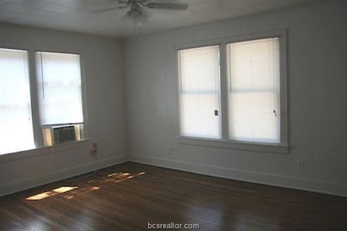 Empty room featuring a ceiling fan, dark wood-styl