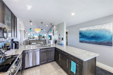 Kitchen with a sink, appliances with stainless steel finishes, dark brown cabinetry, light stone countertops, and a peninsula