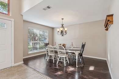 Dining room featuring healthy amount of natural light, a chandelier, and dark wood-style floors