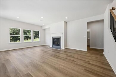 Unfurnished living room featuring stairs, wood finished floors, a glass covered fireplace, and recessed lighting