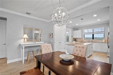 Dining room featuring a chandelier, crown molding, recessed lighting, light wood-style flooring, and baseboards