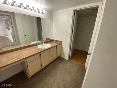 Bathroom with vanity, carpet flooring, and baseboa