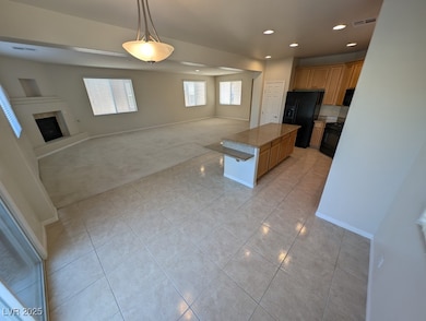Kitchen with open floor plan, pendant lighting, black appliances, light carpet, and a fireplace