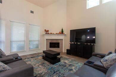Expansive living room with tall ceilings, large windows, and a focal-point fireplace. The layout easily accommodates multiple seating arrangements and offers abundant natural light.