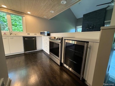 Kitchen with white cabinetry, wine cooler, stainless steel appliances, recessed lighting, and dark wood-type flooring