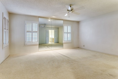 Primary bedroom featuring carpet, a textured ceiling, and a ceiling fan