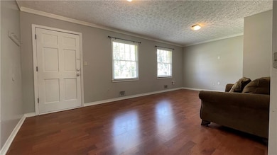 Living area with a textured ceiling, crown molding, and dark wood finished floors