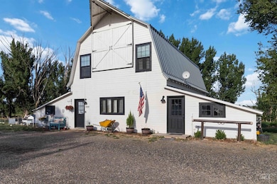 View of front of property with a gambrel roof, a barn, and a metal roof