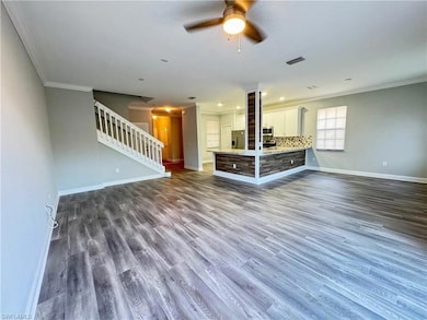 Unfurnished living room with crown molding, stairs