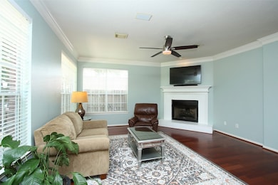 Cheerful den has a corner fireplace, a ceiling fan, and crown molding.