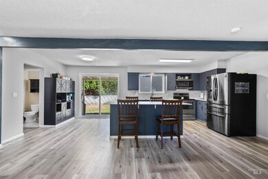Kitchen with appliances with stainless steel finishes, light wood-style flooring, a kitchen breakfast bar, backsplash, and open shelves