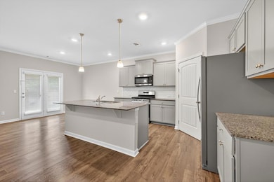 Kitchen featuring gray cabinetry, crown molding, tasteful backsplash, appliances with stainless steel finishes, and wood finished floors