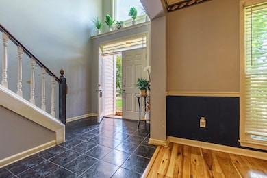 Foyer featuring stairway, plenty of natural light, and dark wood-style flooring