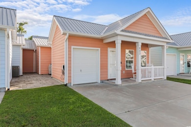 View of front of home featuring metal roof, concrete driveway, a porch, central AC unit, and a garage