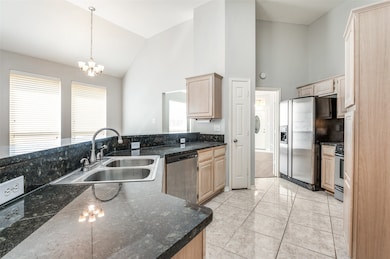 Kitchen featuring high vaulted ceiling, light brown cabinets, stainless steel appliances, light tile patterned floors, and decorative light fixtures