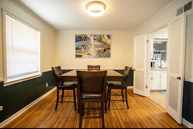 Dining space with wood finished floors, ornamental molding, baseboards, and a textured ceiling