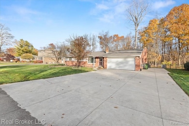 View of front facade featuring concrete driveway, a chimney, an attached garage, and brick siding
