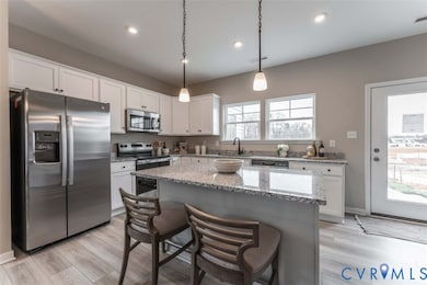 Kitchen with appliances with stainless steel finishes, light stone counters, decorative light fixtures, light wood-type flooring, and recessed lighting