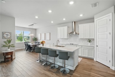 Kitchen with wall chimney exhaust hood, a sink, ba