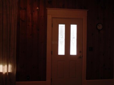 Lovely front door and knotty pine walls in living 