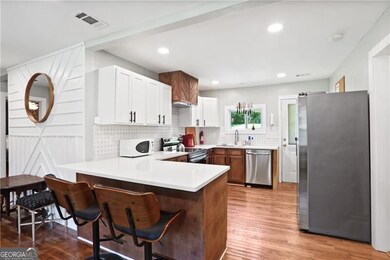 Kitchen with stainless steel appliances, a peninsula, a sink, light wood-type flooring, and backsplash
