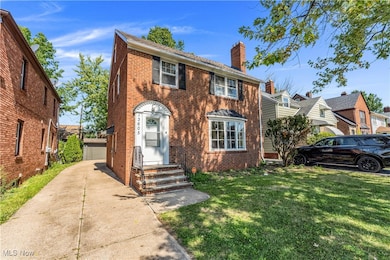 View of front of property featuring brick siding, an outdoor structure, a chimney, and a front lawn