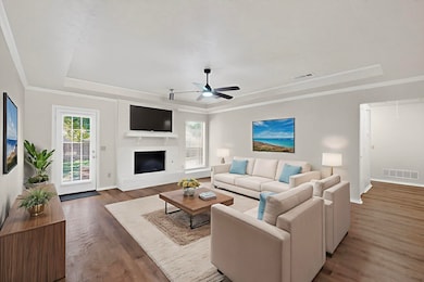 Living area with a raised ceiling, wood finished floors, healthy amount of natural light, ornamental molding, and attic access