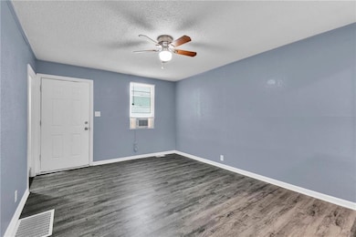 Unfurnished room featuring dark wood finished floors, ceiling fan, and a textured ceiling