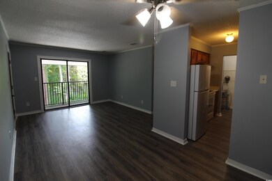 Unfurnished living room with a textured ceiling, ceiling fan, dark wood-style flooring, and crown molding