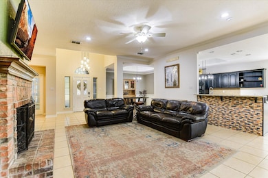 Living room featuring a ceiling fan, a chandelier, light tile patterned floors, a textured ceiling, and a fireplace