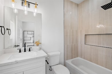 Modern bath featuring vertically stacked porcelain tile, inset niche detailing, and a quartz vanity with matte black fixtures balanced by warm accent lighting.