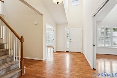 Entryway with stairway, light wood-type flooring, and a high ceiling
