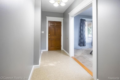 Hall with baseboards and a chandelier