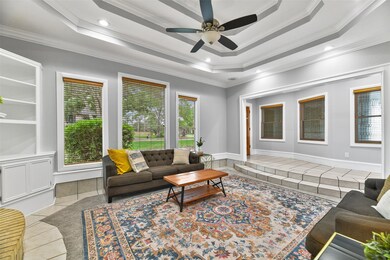 Two steps lead down from the foyer into this sunken living room with plush carpet that was replaced in 2021, a tile border, designer paint, and an impressive triple-trayed ceiling with a lighted ceiling fan, recessed lighting, and built-in speakers.