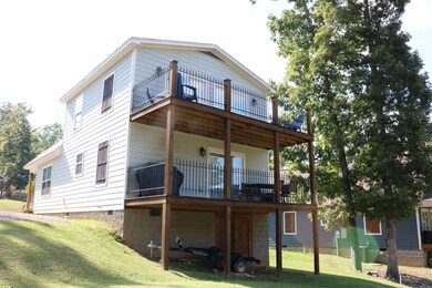 Back of property featuring a lawn and a wooden dec