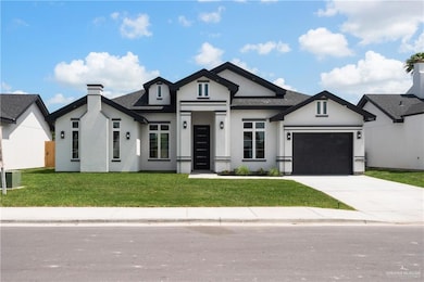 View of front of property with stucco siding, an attached garage, driveway, a front lawn, and a chimney