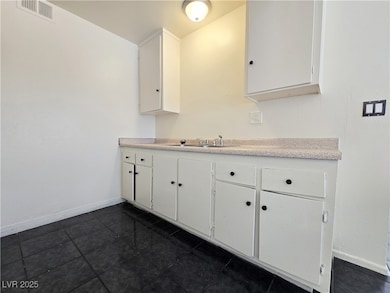 Kitchen with baseboards, visible vents, white cabi
