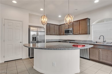 Kitchen featuring stainless steel appliances, a chandelier, light tile patterned floors, dark stone counters, and recessed lighting